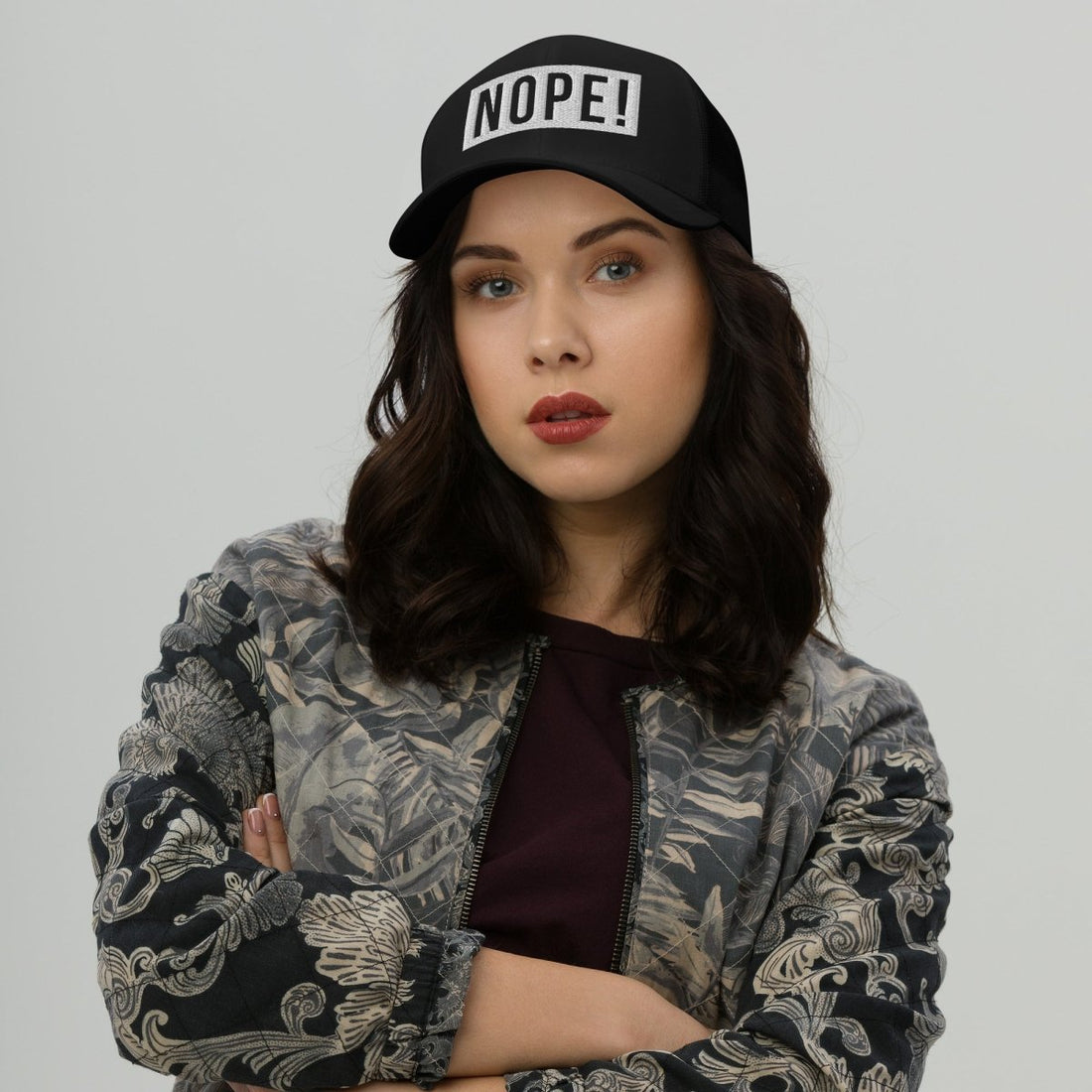 Woman with crossed arms waeing a NOPE! Culture hat looking directly at the lens